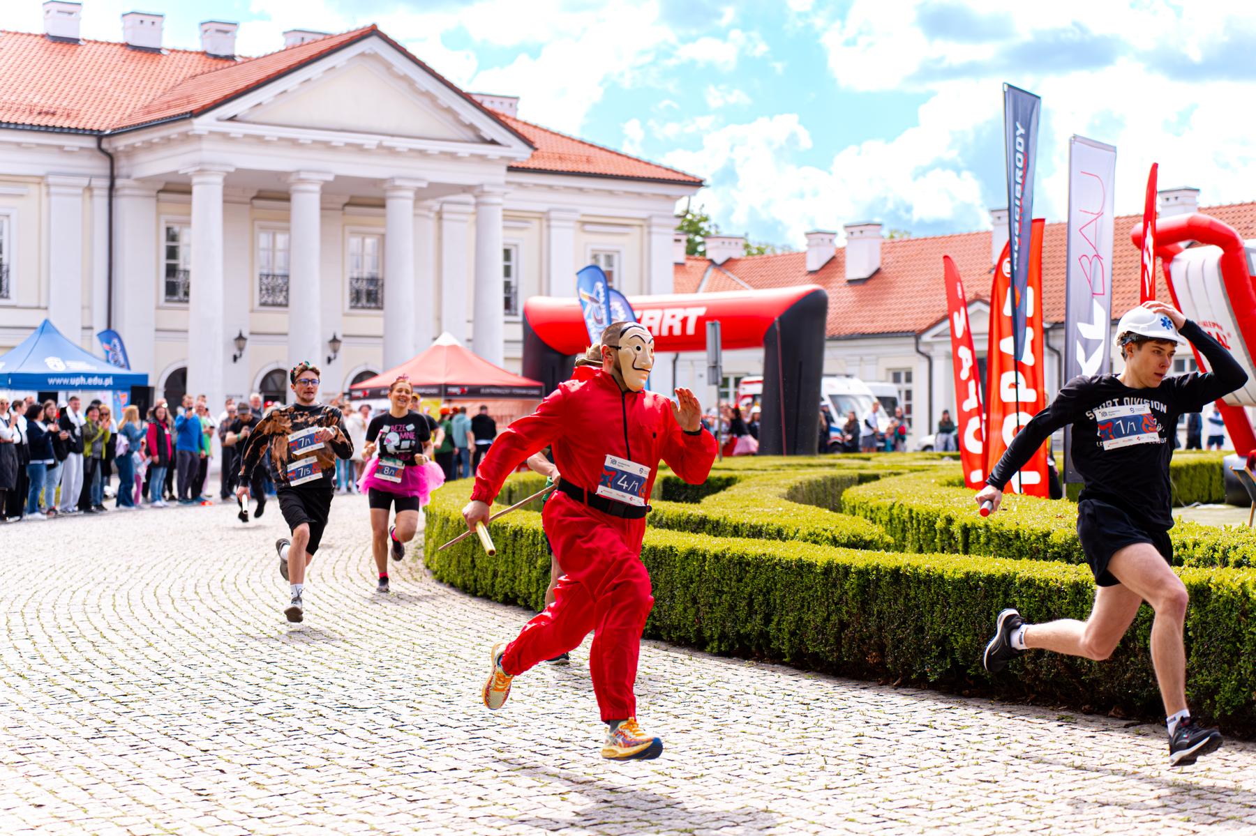 Uczestnicy biegu biegną w przebraniach i maskach.
